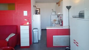 Una cocina compacta con una pared roja de acento, un refrigerador blanco, un fregadero y un microondas.