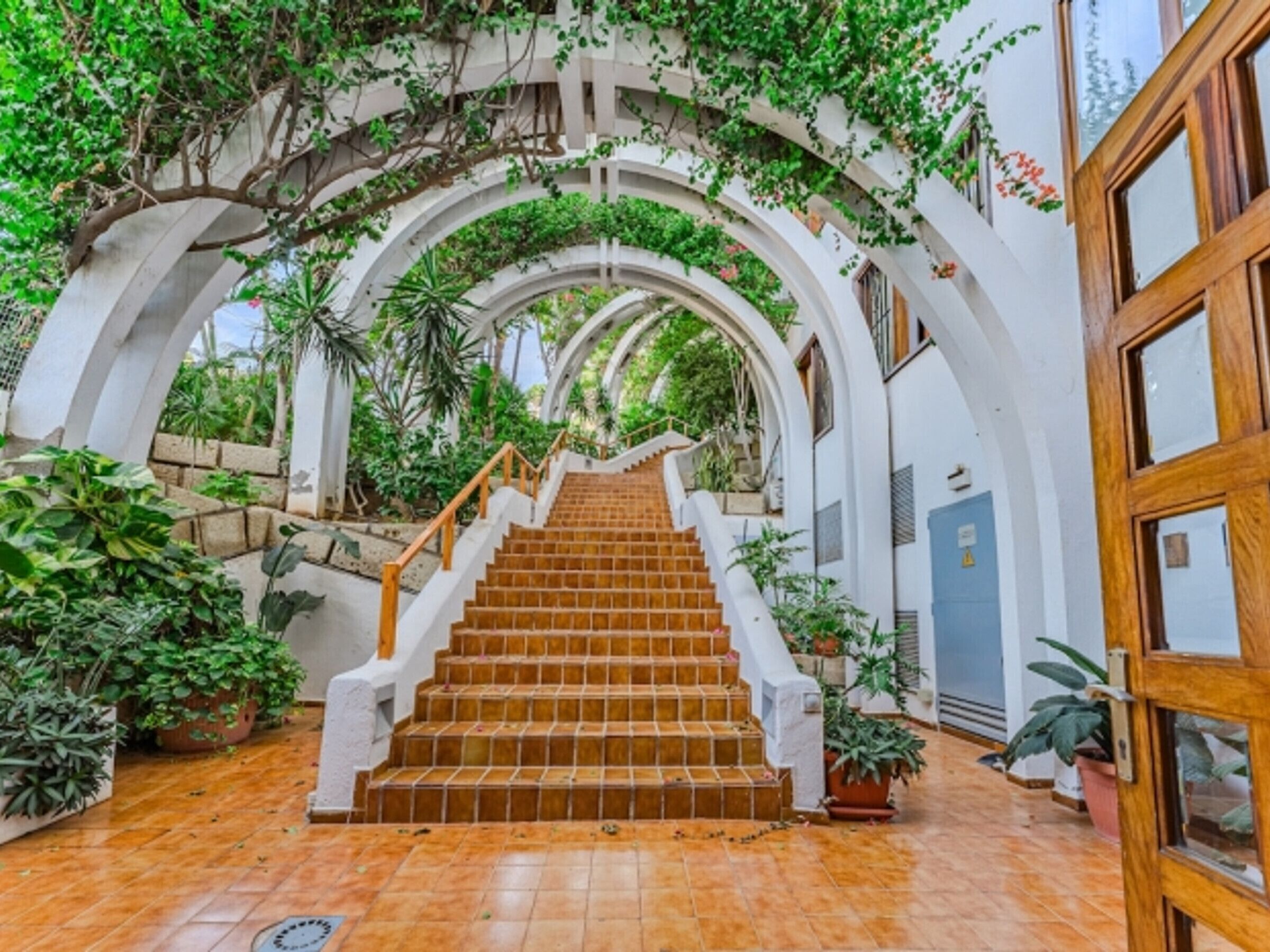 A staircase with white railings and a wooden handrail leading to a door.