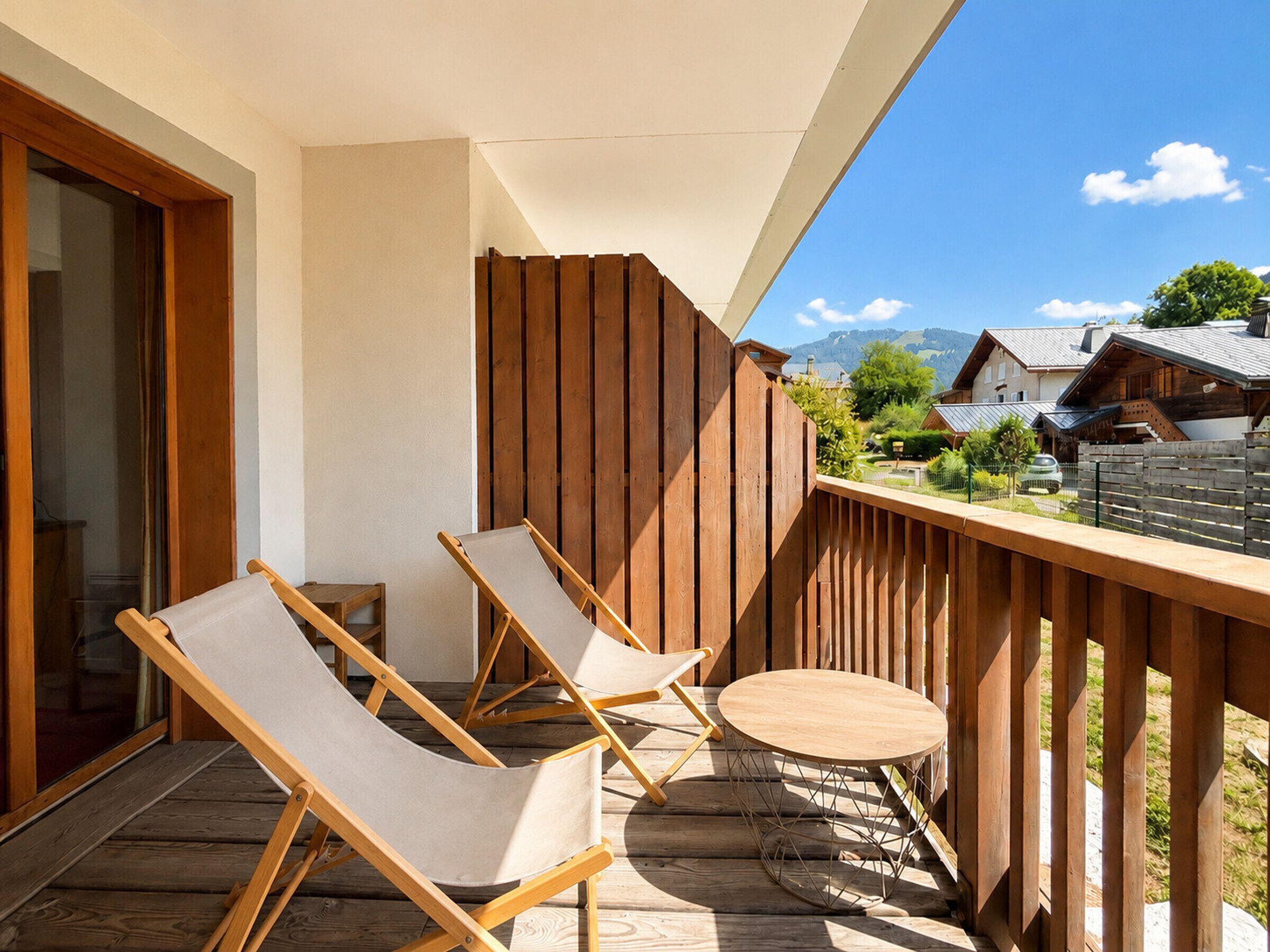 Ein Balkon mit zwei Liegestühlen und einem kleinen runden Tisch, mit Blick auf eine gebirgige Landschaft.