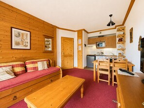 A cozy room with a wooden sofa, a wooden table, and a kitchen area with wooden cabinets and a microwave. - Cozy apartment, pets welcome - 4 guests (Notre-Dame-de-Bellecombe)