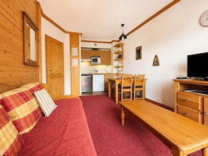 Una habitación acogedora con un sofá de madera, una mesa de comedor y un televisor.