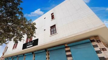 A building with a sign reading 'Collection 5 commercial services,' blue shutters, and a clear blue sky.