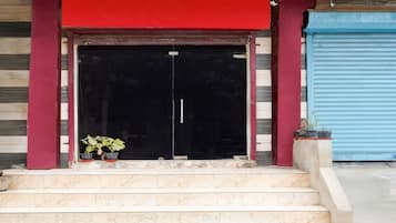 A hotel entrance with a red awning, a black double door, and a set of marble steps leading up to the entrance.
