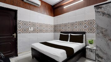 A modern bedroom with a bed, a nightstand, a potted plant, and a wooden door.
