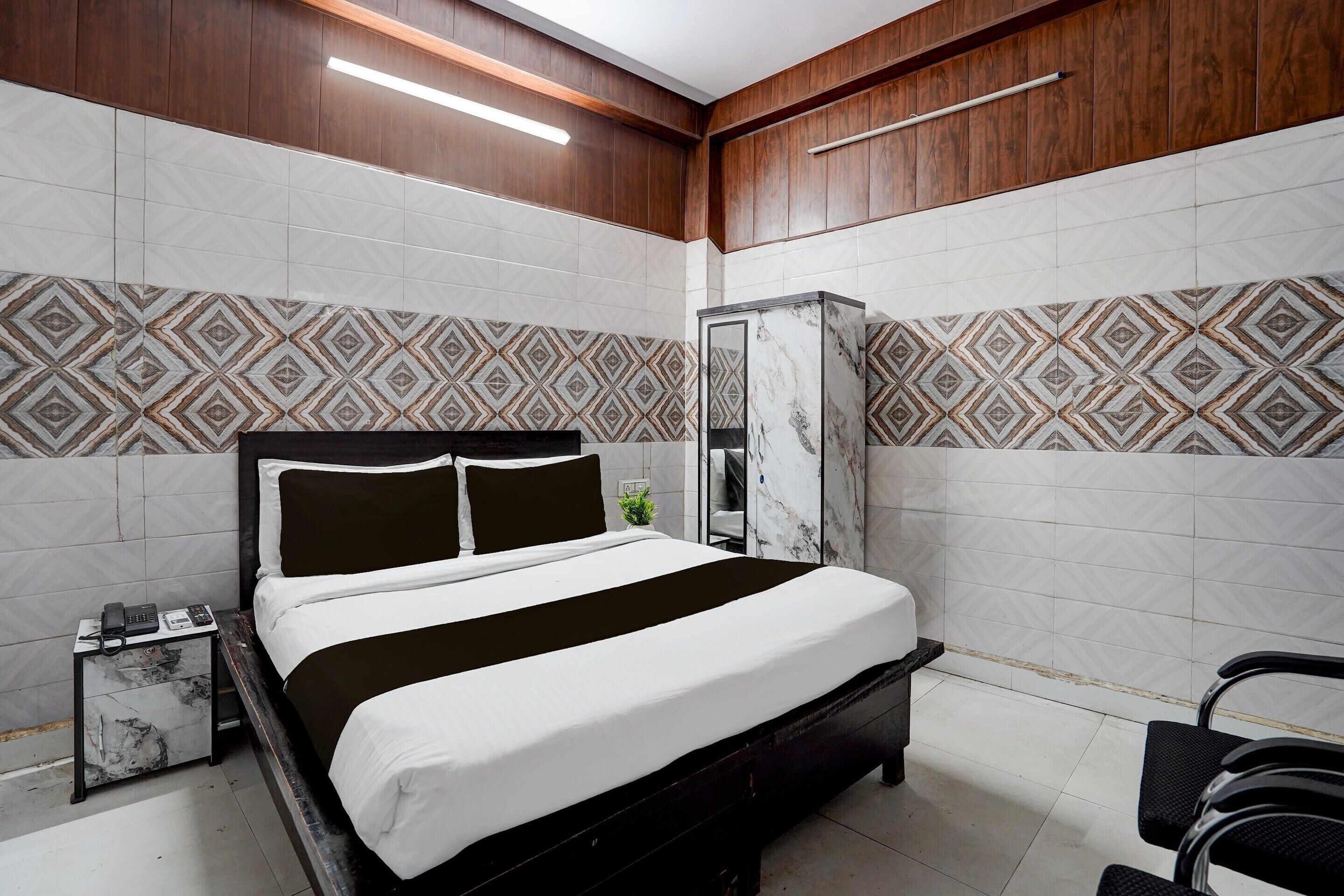 A modern hotel room with a bed, bedside table, and a wardrobe.