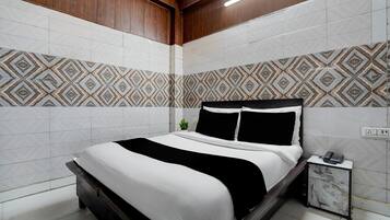 A modern bedroom with a bed, bedside table, and patterned wall tiles.