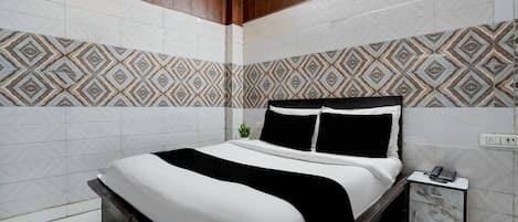 A modern bedroom with a bed, bedside table, and patterned wall tiles.