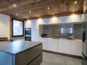 Eine moderne Küche mit Holzboden, eingebauten Geräten und einem großen Fenster.