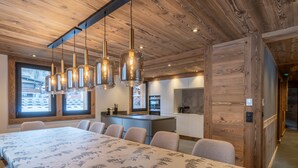 A modern interior with a long dining table, multiple chairs, and hanging pendant lights. - Chalet with pets - 14 guests (Les Gets)