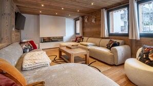 A cozy living room with a sofa, a coffee table, and a fireplace. - Chalet with pets - 14 guests (Les Gets)