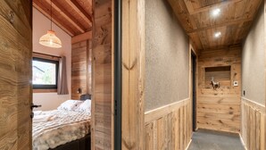 A wooden interior with a bed, a hanging light fixture, and a wall-mounted decoration. - Chalet with pets - 14 guests (Les Gets)