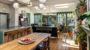 Una cucina con un tavolo in legno, un piatto di frutta e una moderna lampada a sospensione.