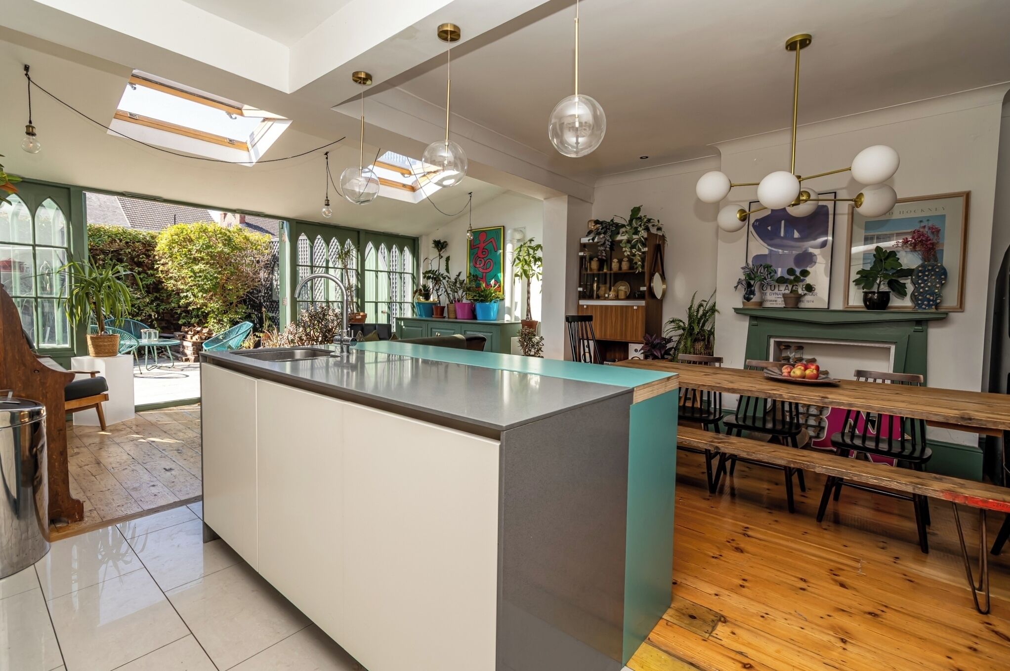 A spacious kitchen with a central island, large windows, and a dining area with wooden flooring.