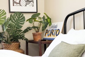 Ein Bett mit Kissen, ein gerahmtes Bild an der Wand und ein Schild mit der Aufschrift 'Porto'.