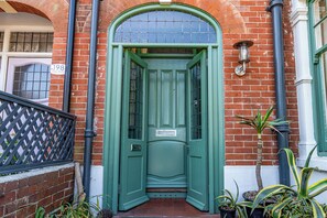 A green door with a white plaque, a brick wall, and a metal gate. - Design-Led Edwardian Park-side Home Portsmouth - Holiday Home (Portsmouth)