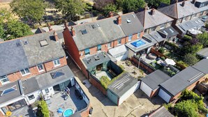 Un quartiere residenziale con diverse case, alcune dotate di antenne paraboliche, una piscina e un cortile recintato.