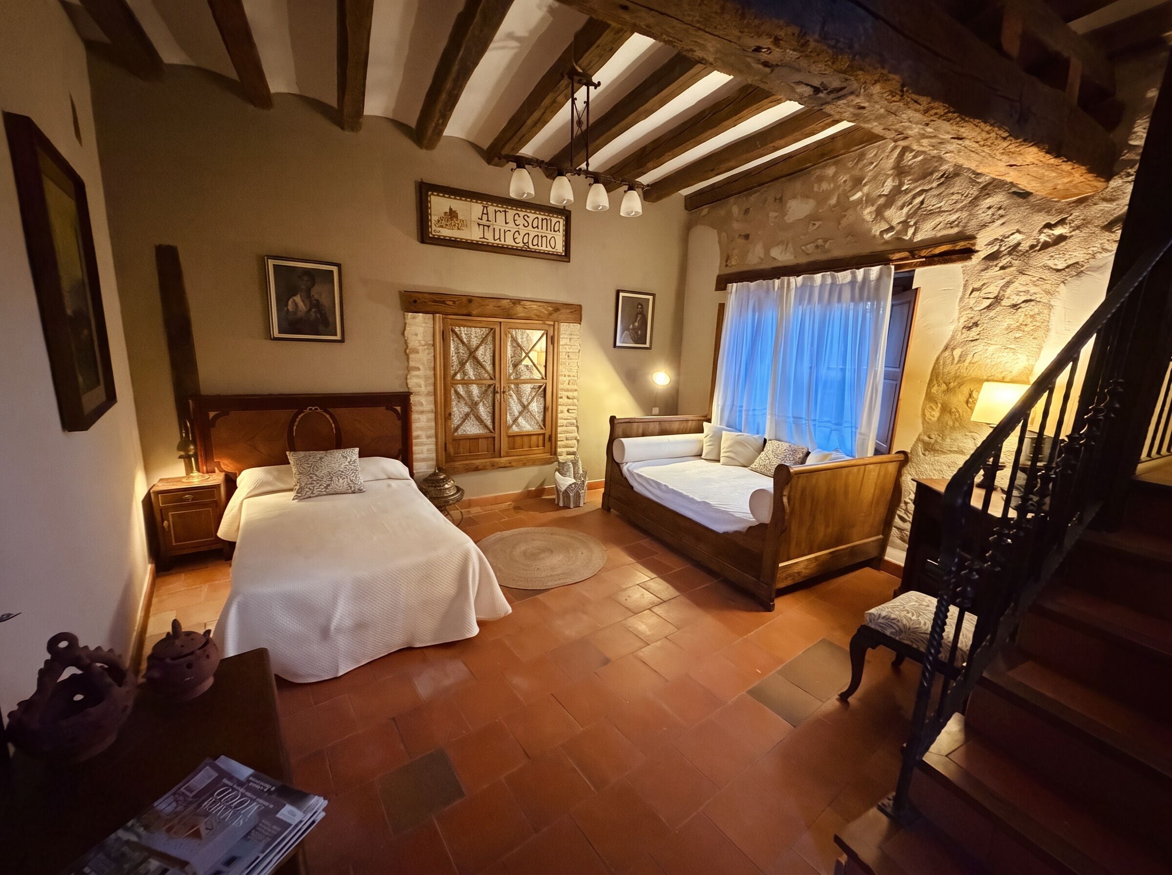 Un dormitorio con dos camas, una escalera de madera y una pared de piedra.