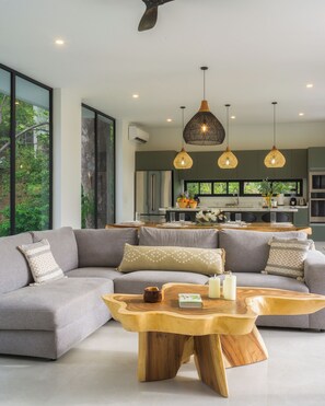 A modern living room with a sectional sofa, a wooden coffee table, and pendant lighting. - Casa Joanna | Luxury Jungle Retreat in Pacifico Resort | Private Pool (Pacifico Resort Lot 35)