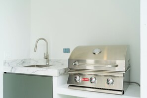 Una cocina con campana de acero inoxidable, un lavamanos y encimera de mármol.