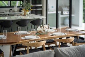 A dining table set with plates, glasses, and a centerpiece. - Casa Joanna | Luxury Jungle Retreat in Pacifico Resort | Private Pool (Pacifico Resort Lot 35)
