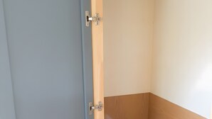 Un baño pequeño con inodoro de madera, una toalla colgada en la puerta y un lavamanos con un jabonera.