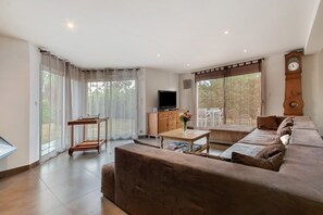 Amplia sala de estar con un sofá grande, un televisor y un mueble de madera.