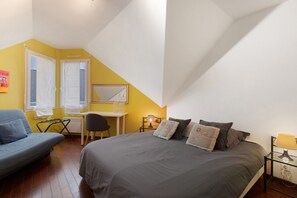 A bedroom with a bed, a desk, a chair, and a couch.