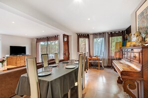 A dining area with a table set for four, a television on a cabinet, and a clock on the wall.