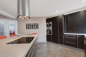 Una cocina moderna con una isla central, muebles oscuros y electrodomésticos de acero inoxidable.