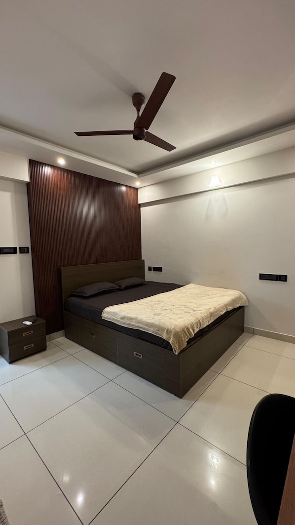 A modern bedroom with a bed, a nightstand, a ceiling fan, and a wall-mounted light.