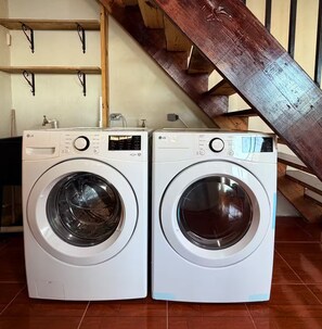 Deux lave-linge LG à chargement frontal se trouvent dans une pièce dotée d’un escalier en bois et d’un sol carrelé.