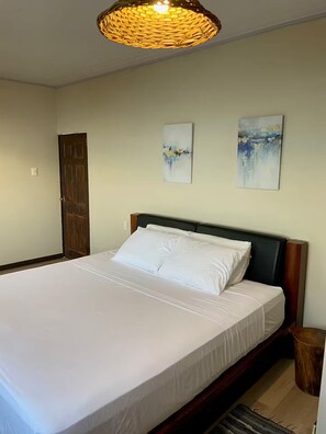 Ein Schlafzimmer mit einem großen Bett, einer Holztür und zwei an der Wand hängenden Bildern.