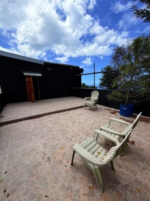 An outdoor patio area with two chairs and a potted plant. - Paramin View- 2 BR Ocean and Mountain Views Retreat (Diego Martin Regional Corporation)