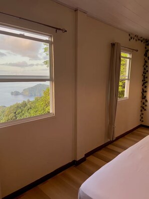 Ein Zimmer mit großem Fenster und Blick auf ein Gewässer und grüne Vegetation.