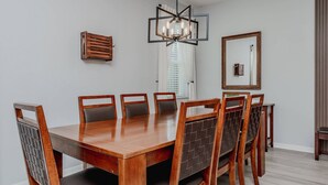 A dining room with a wooden table and chairs, a chandelier, and a mirror on the wall. - 5BR Veranda Palms Home Near Disney for 14 (Kissimmee)