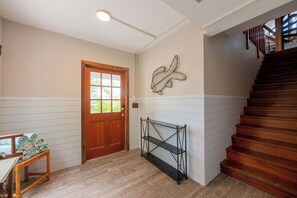 Ein Flur mit einer Holztür, einem Wandregal und einer Treppe.
