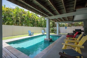 Ein Swimmingpool mit Liegestühlen und einem Grillbereich.