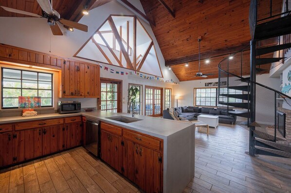 A spacious kitchen with wooden cabinets, a central island, and a large window. - Tree Top Bungalow: 2-min walk to beach access, Private Pool (Anna Maria)