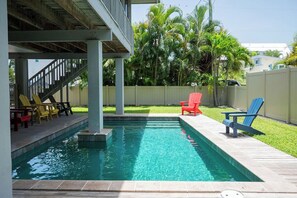 A swimming pool with a covered deck area, surrounded by a fence and palm trees. - Tree Top Bungalow: 2-min walk to beach access, Private Pool (Anna Maria)
