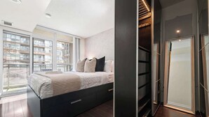 Ein modernes Schlafzimmer mit einem großen Bett, integrierten Stauraumlösungen und Blick auf die Stadt durch raumhohe Fenster.