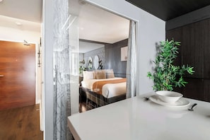 Une chambre d’hôtel moderne avec un lit, une table à manger et une plante.
