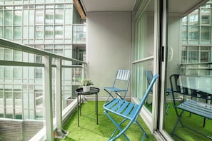Un balcon avec une petite table, deux chaises et un pot de fleurs.
