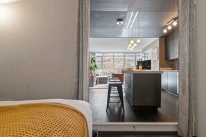 A modern interior with a kitchen area, a dining space, and a view through a window. - Stunning Condo Near CN Tower & Waterfront Parking | Parking Available (Toronto)