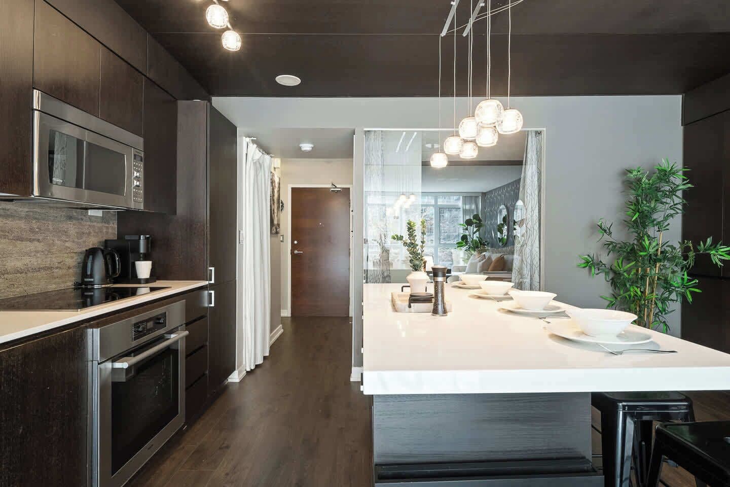 A modern kitchen with dark wood cabinets, stainless steel appliances, and a central island with seating.