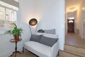 A room with a white sofa, a round floor lamp, and a potted plant. - Stylish, cozy Refurbished Flat Near Stratford - Pass the Keys (London)