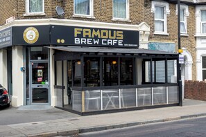 Café Famous Brew mit schwarzer und goldener Fassade, großen Fenstern und einem gut sichtbaren Eingang.