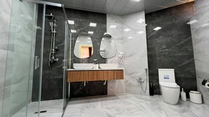 Un baño moderno con ducha acristalada, tocador de madera y un inodoro.