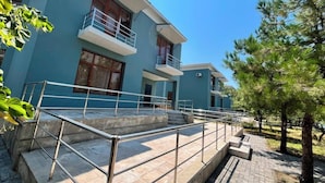 Un edificio de varios pisos con un balcón, una escalera y un patio empedrado.