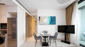 A modern living room with a dining area, a flat-screen TV, and a large abstract painting on the wall. - Chic Address JBR Haven w/ Marina View (Dubai)