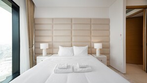 A hotel room with a large bed, two bedside tables, a headboard, and a view through a window. - Chic Address JBR Haven w/ Marina View (Dubai)